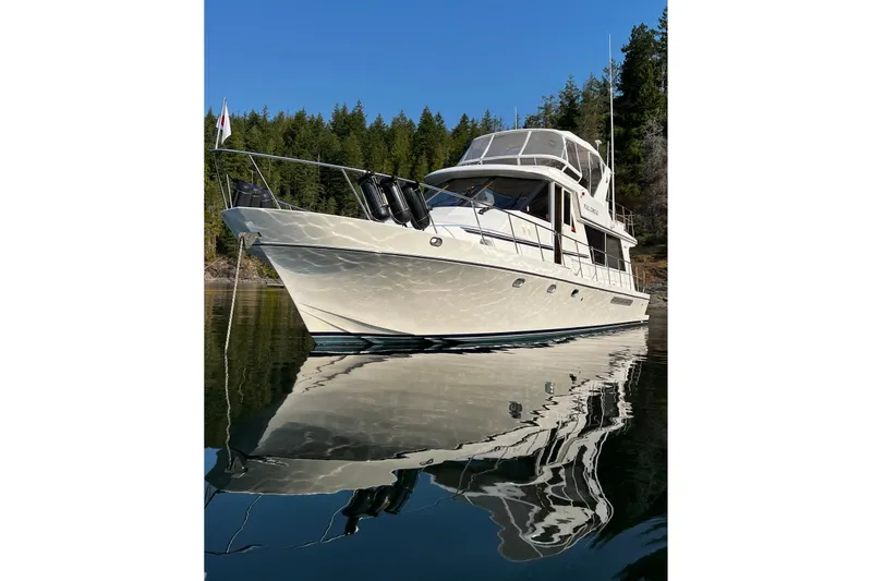 Slide: The Image of 2002 Canoe Cove 50 Pilothouse Motor Yacht on calm water, surrounded by forest. - 1
