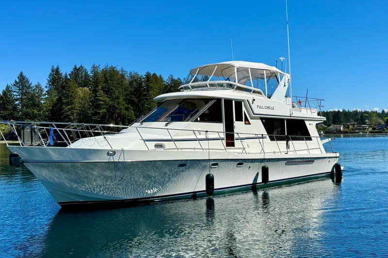 Slide: The Image of 2002 Canoe Cove 50 Pilothouse Motor Yacht on serene water, surrounded by trees. - 5