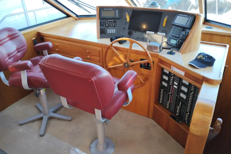 Slide: The Image of Pilothouse interior of 2002 Canoe Cove 50 Motor Yacht with red chairs and wooden steering wheel. - 60