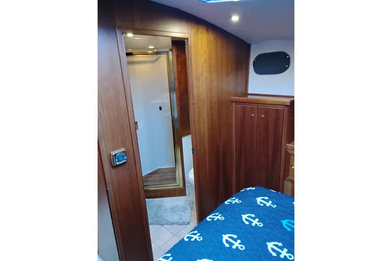 Slide: The Image of Interior of 2002 Canoe Cove 50 Pilothouse Motor Yacht with wood paneling and nautical bedding. - 72