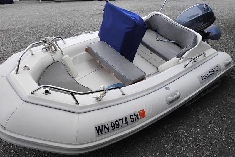 Slide: The Image of Small inflatable boat with Yamaha motor, named "Full Circle," on gravel surface. - 92