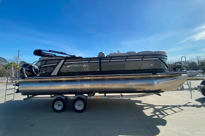 Slide: The Image of 2024 Starcraft SLS 3 pontoon boat on trailer under clear blue sky. - 3
