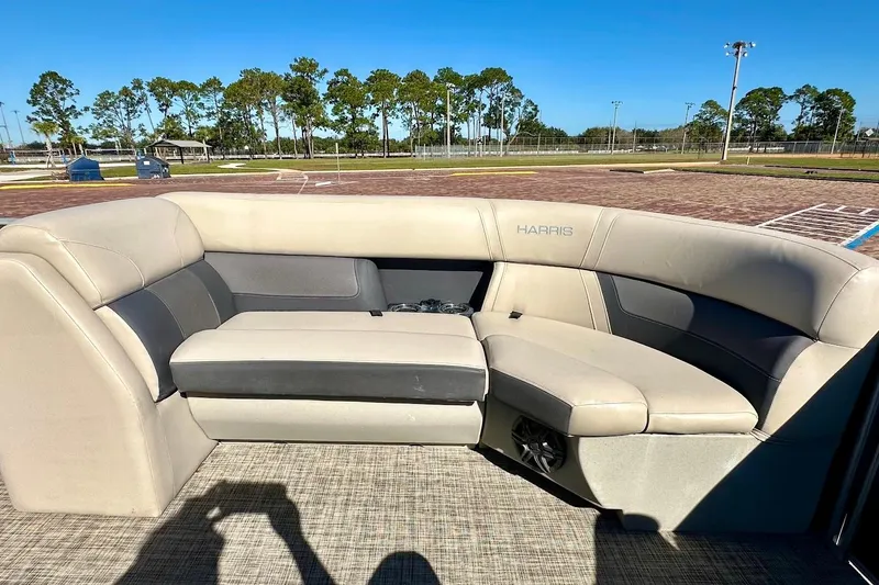 Slide: The Image of 2023 Harris Cruiser 230 boat interior with beige and gray seating under clear blue sky. - 15