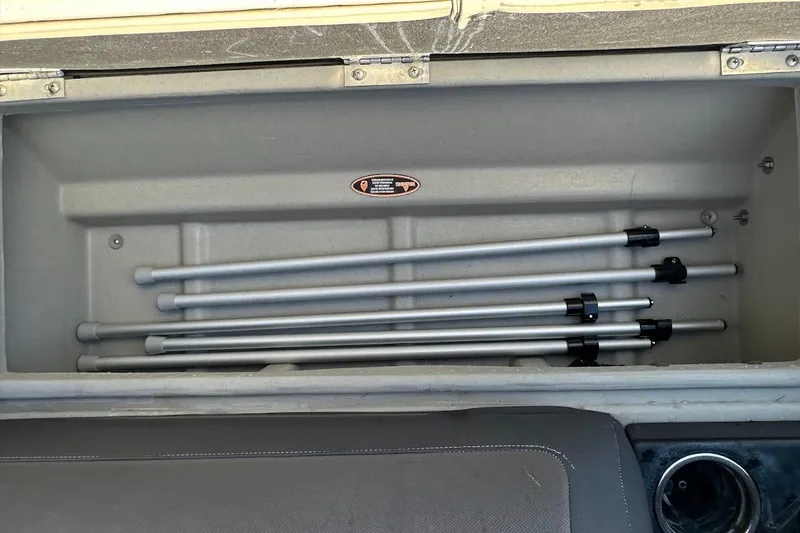 Slide: The Image of Storage compartment with metal poles in a 2023 Harris Cruiser 230 boat. - 32