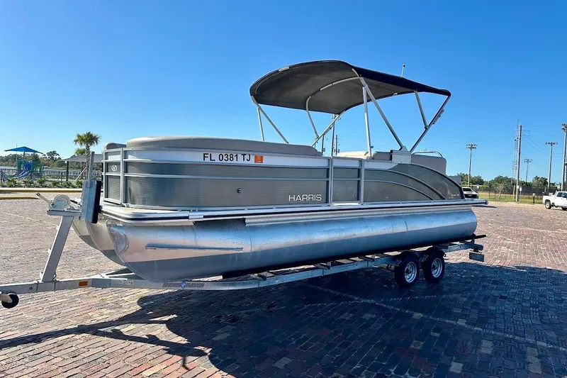 Slide: The Image of 2023 Harris Cruiser 230 pontoon boat on trailer, parked on brick pavement. - 4