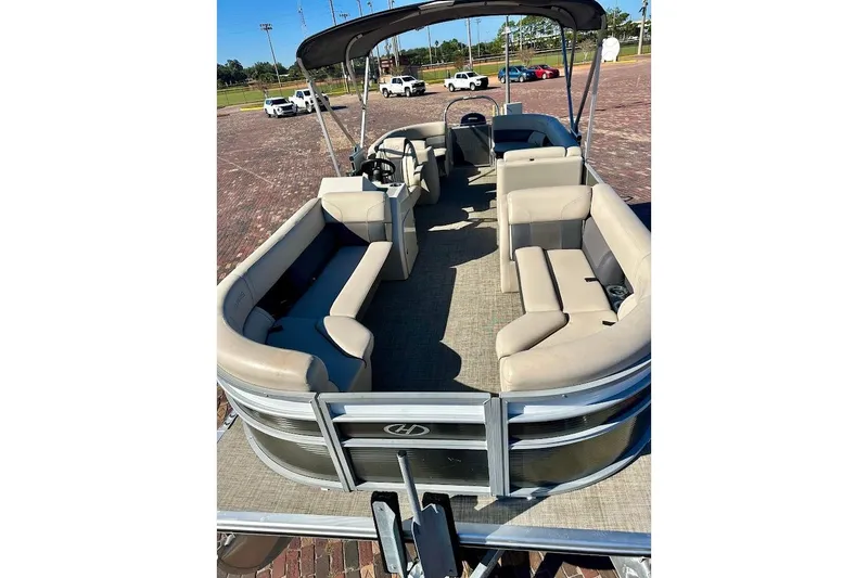 Slide: The Image of 2023 Harris Cruiser 230 pontoon boat with spacious seating and canopy, parked on brick pavement. - 7