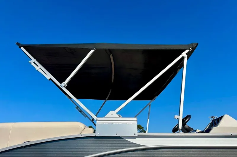 Slide: The Image of 2023 Harris Cruiser 230 boat with a raised black canopy against a clear blue sky. - 9