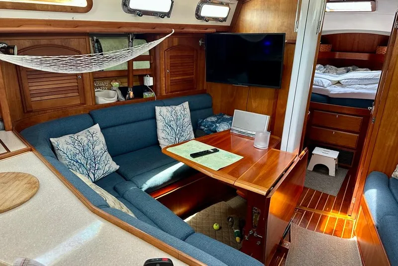 Slide: The Image of Cozy interior of 2002 Sabre 402 sailboat with blue seating, wooden table, and TV. - 26
