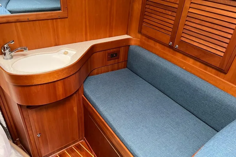 Slide: The Image of 2002 Sabre 402 yacht interior with wooden cabinetry, blue cushioned seating, and a compact sink. - 41