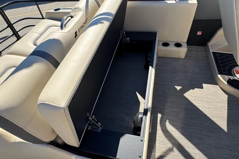 Slide: The Image of 2026 Starcraft RX 25 Q DC boat interior with open storage compartment and beige seating. - 13
