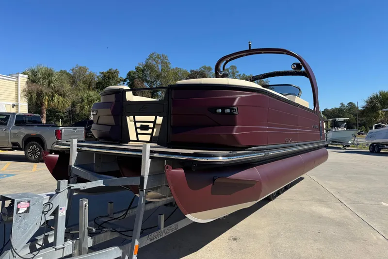 Slide: The Image of 2026 Starcraft RX 25 Q DC pontoon boat on trailer, parked outdoors under clear blue sky. - 2