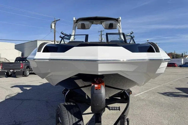 Slide: The Image of 2026 Supra SE boat on trailer in parking lot, under clear blue sky. - 2