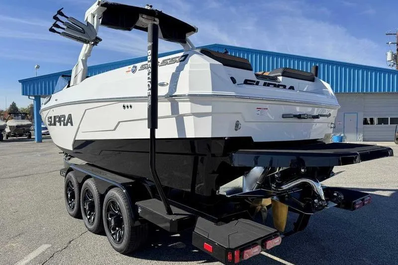 Slide: The Image of 2026 Supra SE boat on trailer, parked outdoors near blue building. - 3