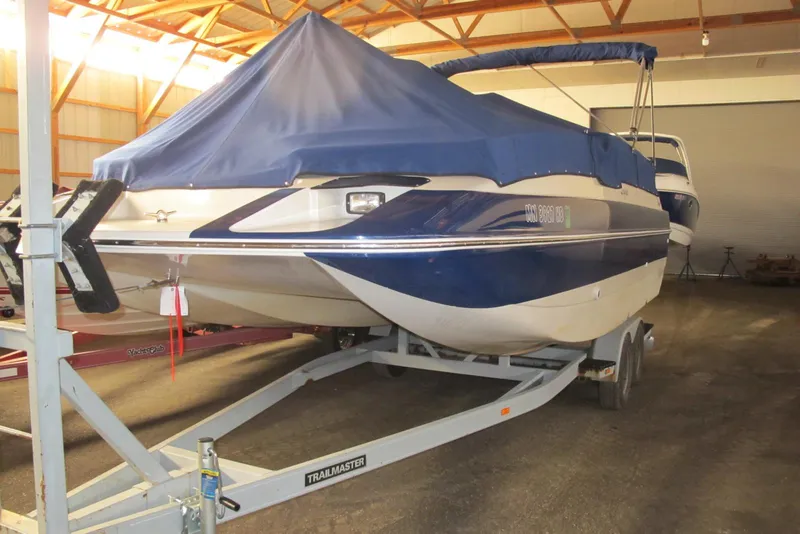 The Image of 1995 Harris FloteBote Legend 240 boat on trailer, covered in blue tarp, stored indoors. - 0