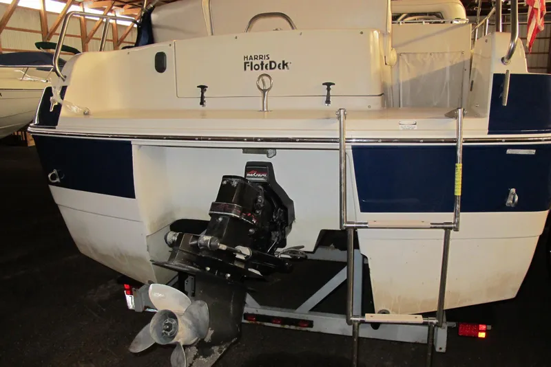 Slide: The Image of 1995 Harris FloteBote Legend 240 boat with outboard motor and ladder in storage. - 3