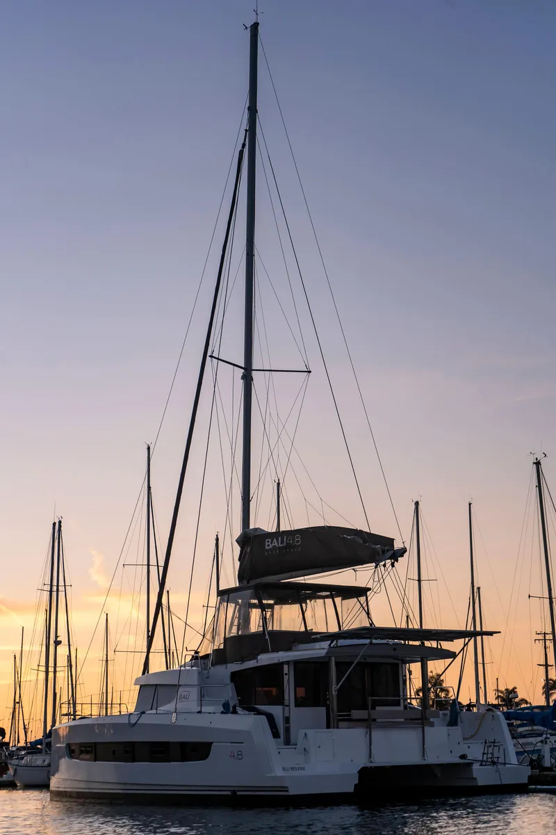 Slide: The Image of Sailing catamaran Bali 4.8, 2021 model, docked at sunset with masts silhouetted. - 6