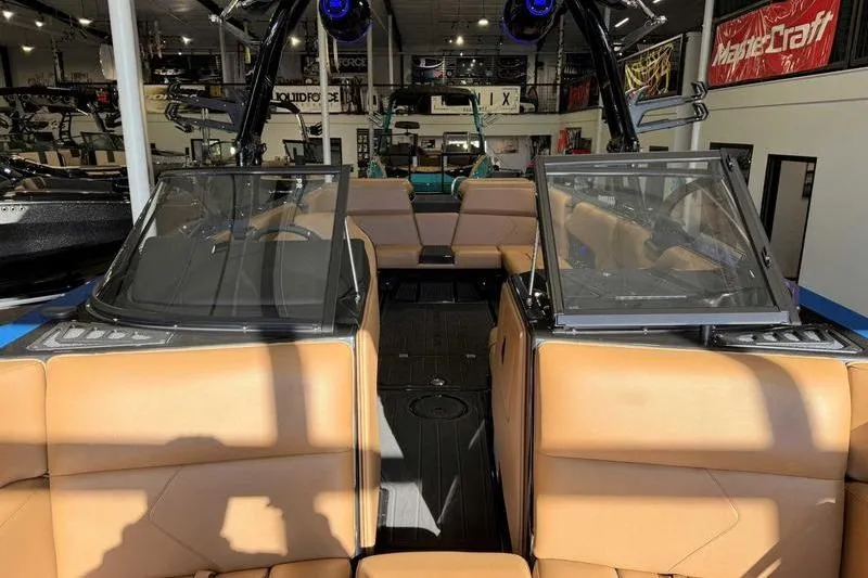 Slide: The Image of 2026 Moomba Tykon boat interior with tan seating and modern design in showroom. - 13