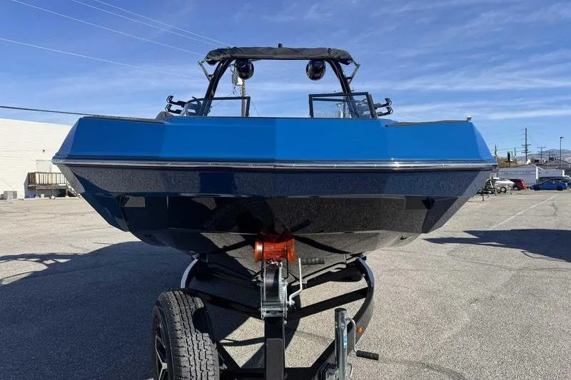 Slide: The Image of 2026 Moomba Tykon boat on trailer, blue and black design, parked outdoors. - 5