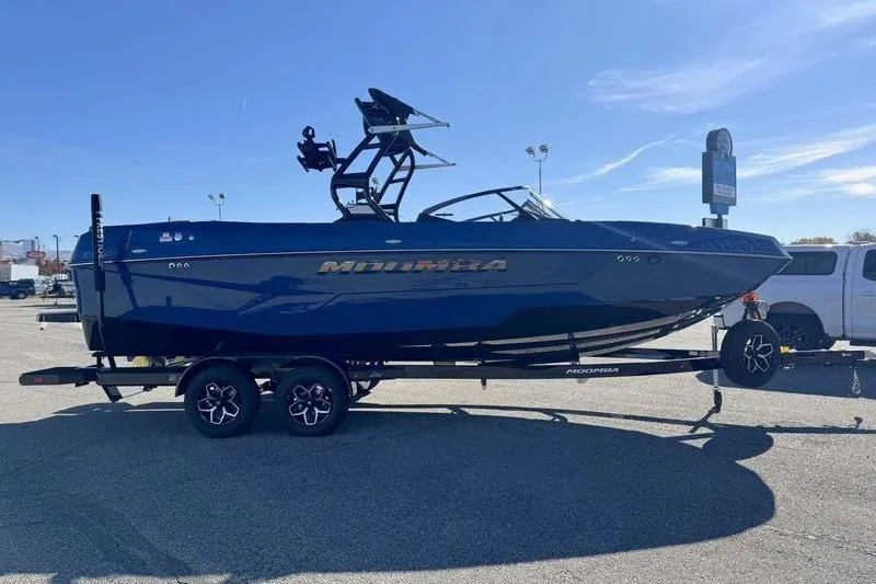 Slide: The Image of 2026 Moomba Tykon boat on trailer, parked in a lot under clear blue sky. - 6
