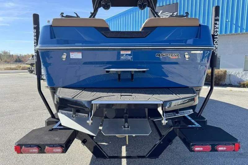 Slide: The Image of 2026 Moomba Tykon boat rear view, blue exterior, on trailer, with Raptor engine branding. - 7