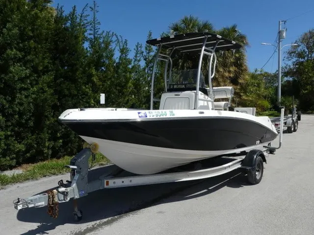 The Image of A 2017 Yamaha 190 FSH boat on a trailer, surrounded by trees and palm trees. - 1