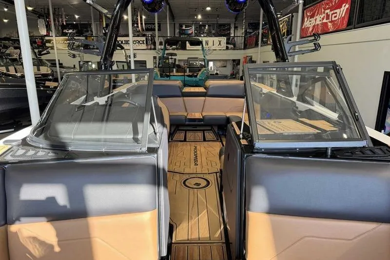Slide: The Image of 2026 Moomba Tykon boat interior with tan and gray seating, open windshield, and wood flooring. - 12