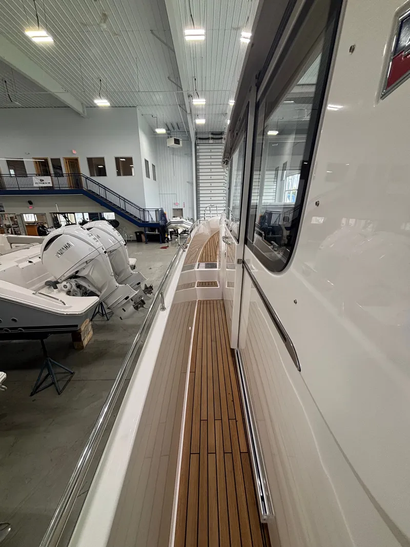 Slide: The Image of 2026 Nimbus Commuter 11 MKII Legacy Edition yacht in a showroom, showcasing sleek design and wooden deck. - 5