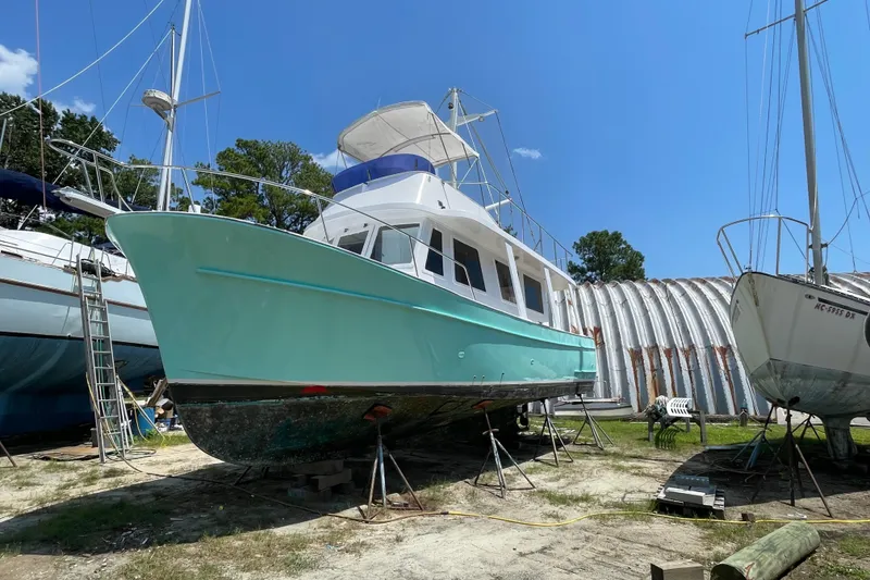 Slide: The Image of 1982 Marine Trader Europa boat docked, featuring a turquoise hull and white upper deck. - 6