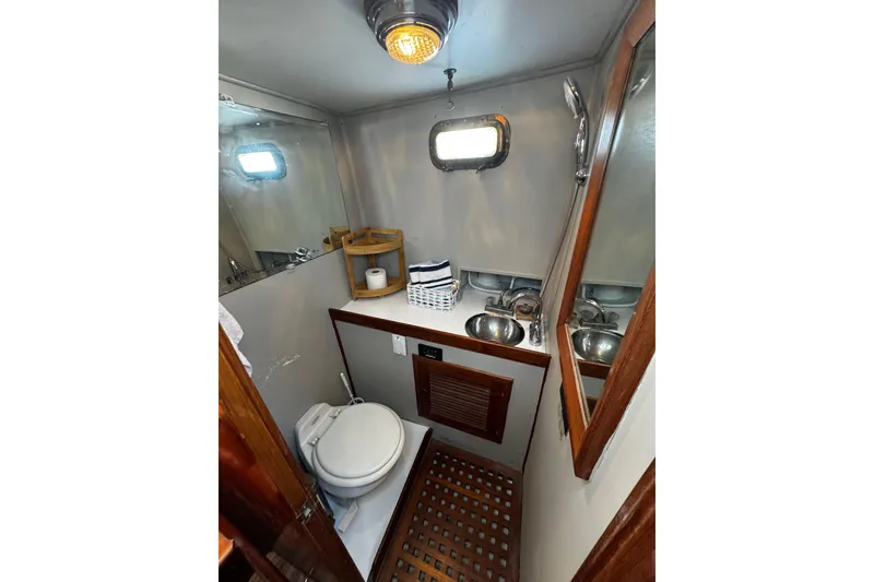 Slide: The Image of Compact bathroom in 1982 Marine Trader Europa yacht with toilet, sink, and mirror. - 85