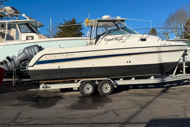 The Image of 2004 Glacier Bay 2670 Isle Runner boat on trailer, parked outdoors under clear blue sky. - 0