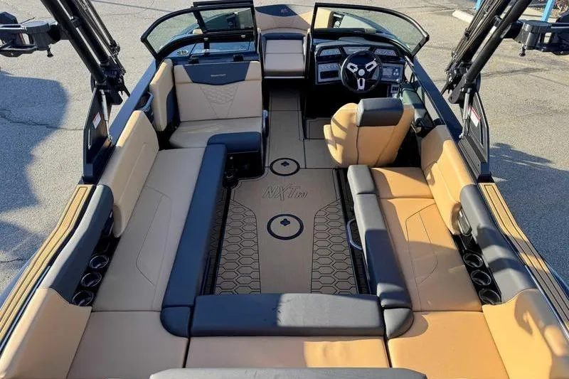 Slide: The Image of 2026 MasterCraft NXT23 boat interior with tan and black seating, modern dashboard, and steering wheel. - 10