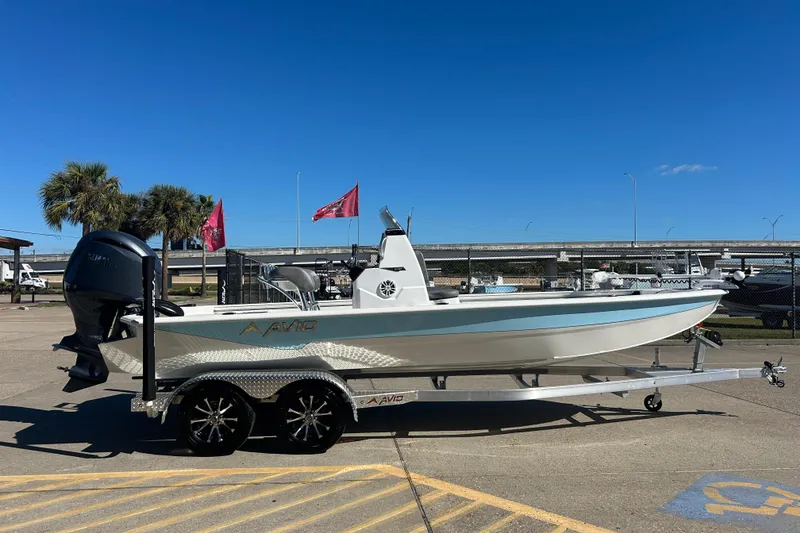 Slide: The Image of 2025 Avid 21 FST boat on trailer, parked outdoors under clear blue sky. - 4
