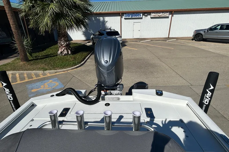 Slide: The Image of Avid 21 FST 2025 boat with motor, parked near palm tree and building. - 8