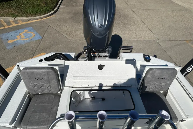 Slide: The Image of 2025 Avid 21 FST boat interior with seating and motor, parked on concrete. - 9