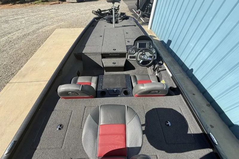 Slide: The Image of 2018 Ranger RT198P boat interior with steering wheel and seating, parked near a blue building. - 24