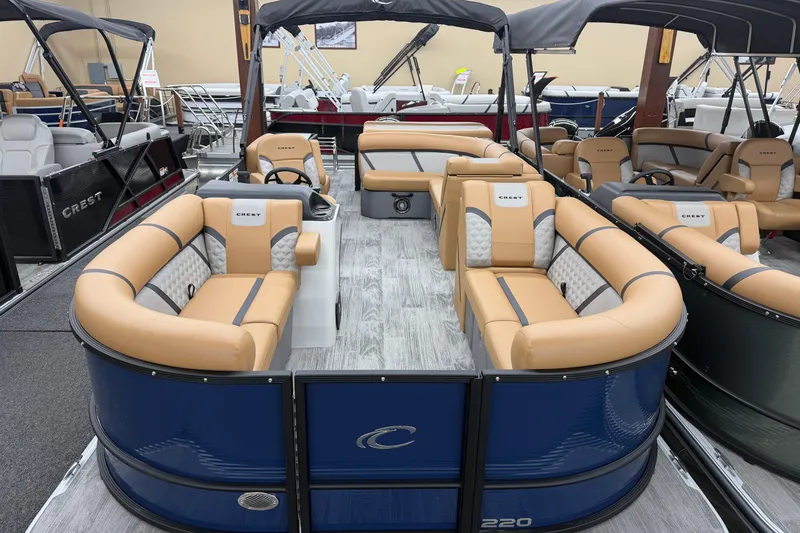 The Image of 2025 Crest Classic 220 pontoon boat with tan seating and blue exterior in showroom. - 1