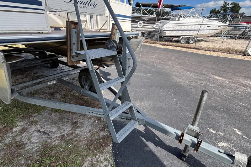 Slide: The Image of 2005 Bentley Pontoons 200 Fish on trailer with metal steps, parked outdoors. - 31