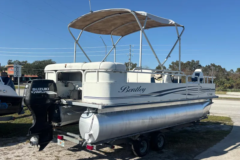 Slide: The Image of 2005 Bentley Pontoons 200 Fish with Suzuki outboard motor on trailer, parked outdoors. - 46
