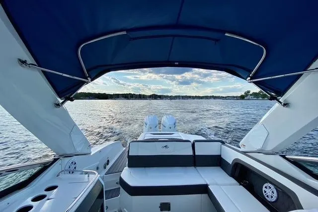 Slide: The Image of 2019 Monterey 305SS Super Sport boat with blue canopy on a serene lake. - 21
