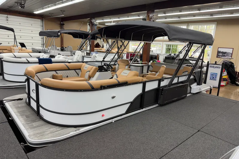 The Image of 2025 Crest Classic 220 pontoon boat with tan seating and black canopy in showroom. - 1