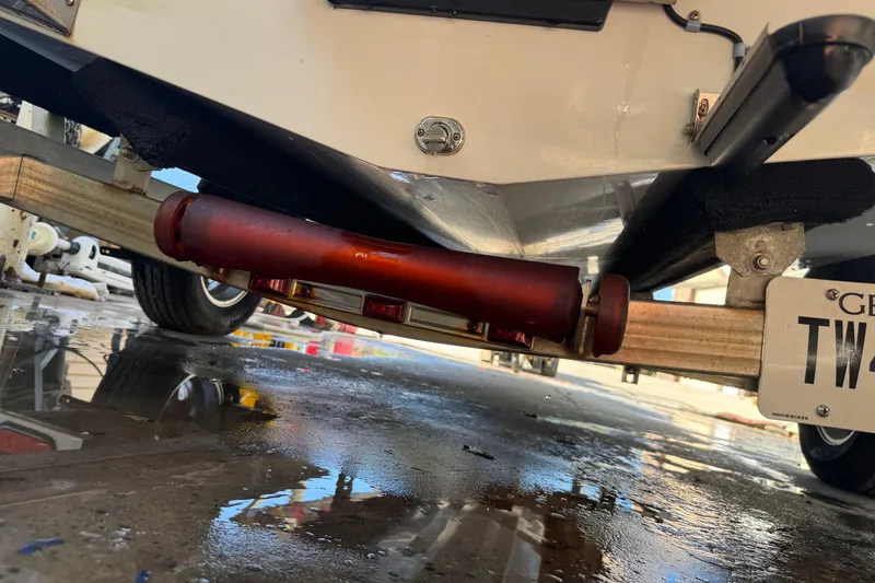 Slide: The Image of 2020 Hell's Bay Marquesa boat trailer underside with visible license plate and wet ground. - 12