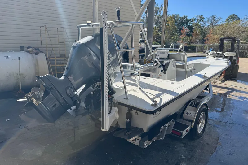 Slide: The Image of 2020 Hell's Bay Marquesa boat with outboard motor on trailer in a sunny yard. - 2