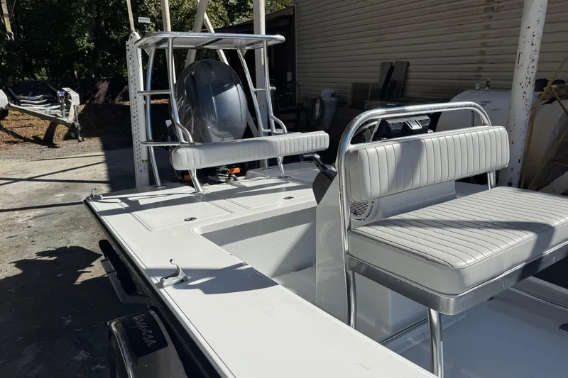 Slide: The Image of 2020 Hell's Bay Marquesa boat with cushioned seating and outboard motor in a sunny setting. - 8