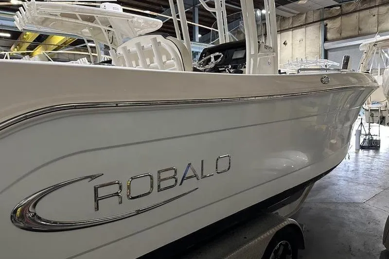 Slide: The Image of 2018 Robalo R242 Explorer boat in a warehouse, showcasing sleek white hull design. - 7
