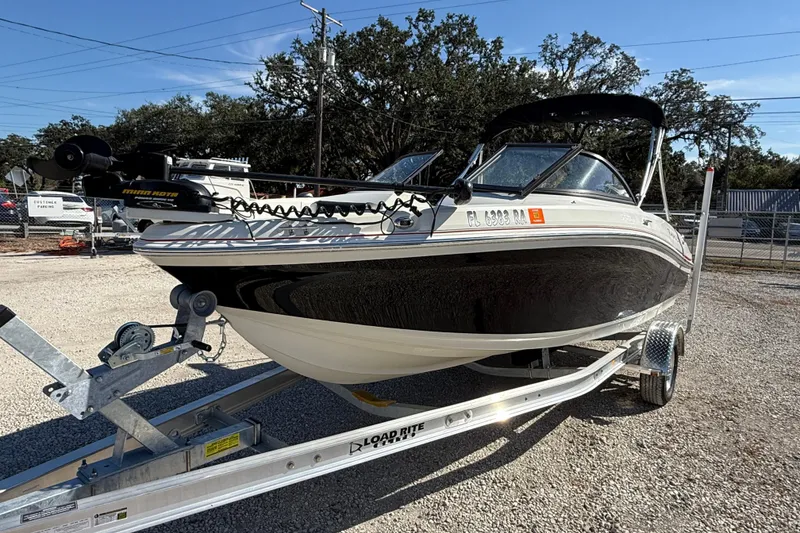 The Image of 2016 Tahoe 550TF boat on trailer, parked outdoors under clear blue sky. - 0