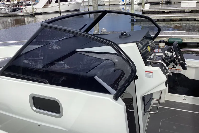 Slide: The Image of 2024 Quarken 27 T-Top V2 boat cockpit with steering wheel and controls at marina. - 22