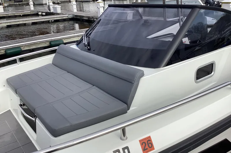 Slide: The Image of 2024 Quarken 27 T-Top V2 boat with sleek gray seating at a marina. - 24