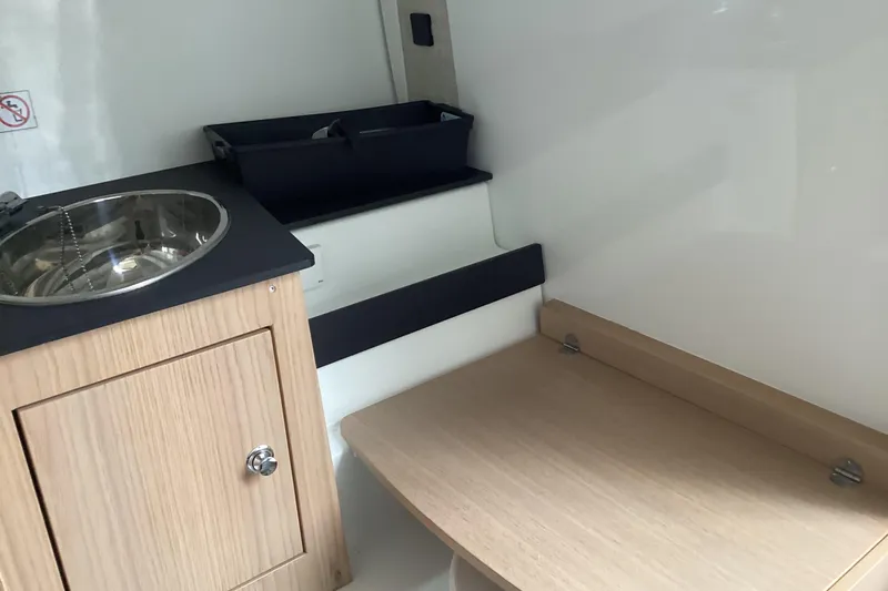Slide: The Image of Interior of 2024 Quarken 27 T-Top V2 featuring a compact sink and wooden cabinetry. - 5
