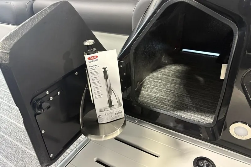 Slide: The Image of Open storage compartment in 2026 Premier 230 Sunsation RL boat with OXO paper towel holder. - 15