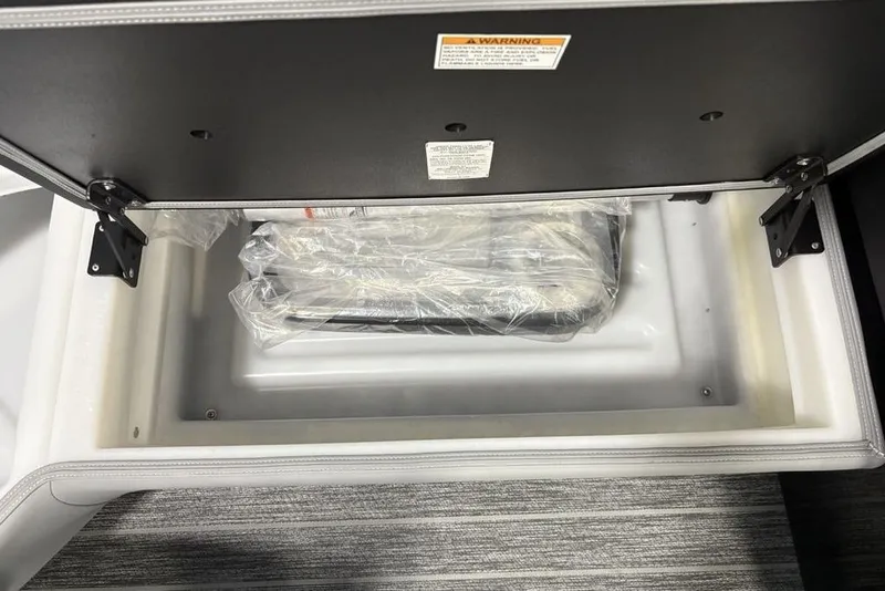 Slide: The Image of Open storage compartment in 2026 Premier 230 Sunsation RL boat, showing packaged items inside. - 8
